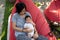 Asian mother holding baby while resting on lazy bag