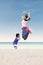 Asian mother jumping with daughter at beach