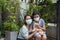 Asian mother and Kid wear mask and playing with dog together in nature park. Thai Woman and dauther greeting and hug at home.