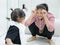 Asian mother making funny gesture to keep her baby girl entertained, while waiting to see the doctor at a hospital