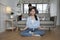 Asian mother meditates and practices yoga wellness, dad and son tease on sofa