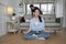Asian mother meditates and practices yoga wellness, dad and son tease on sofa