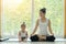 Asian mother practiced yoga by sitting in lotus position at home with a daughter sitting beside while workout at home