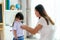 Asian mother preparing kindergarten student uniform to her little daughter for school getting ready for school in living room at