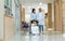 Asian Mother taking care of her little girl daughter get injured, sitting on wheelchair while walking on hallway of hospital,