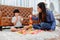 Asian mother work home together with son. Mom and kid play color wooden block. Child creating building toy.