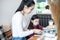 Asian mothers are teaching their daughters to read a book on holidays at home. Educational concepts and activities of the family