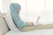 Asian Muslim Islamic woman with hijab happy enjoy online remote work at home with her laptop on the bed