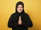 Asian muslim lady smiling and shows greeting gesture against yellow background, concept of islamic celebration of ramadan or eid