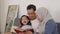 Asian muslim parent, mother, father and child are reading a book at home, happy excited expression, family education concept