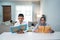 Asian Muslim senior man teaching wife reading Koran or Quran in living room