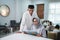 Asian Muslim senior man teaching wife reading Koran or Quran in living room