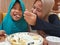 Asian muslim woman eating breakfast with her daughter at cafe, people eating food, happy parent and kid relation