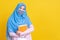 Asian Muslim woman in hijab and wearing medical mask and holding book