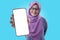 Asian muslim woman looking to camera, smiling and showing empty blank white copy space phone mock up template