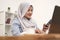 Asian muslim woman work in office, using phone and laptop, happy smiling facial expression, online shopping check out