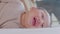 An Asian newborn baby is laying down on a soft white sheet mattress. Starring at his parents and feels sleepy. Adorable chubby boy