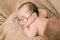 Asian Newborn baby wearing glasses and sleep on brown bed at home, 0-1month-old infant lying in blanket with relax. Adorable baby