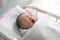 Asian newborn baby yawn in  bassinet at delivery room at hospital