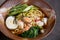 Asian noodle soup with meat, boiled egg, shrimp, spinach. Closeup with selective focus