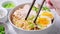 Asian noodle soup ramen with chicken and egg in gray bowl.