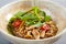 Asian noodles with chicken in beige bowl