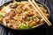 Asian noodles with fried pork belly, mushrooms and napa cabbage in soy sauce close-up in a plate. horizontal