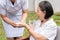 Asian nurse helping sick elderly woman to drink water with medical pill