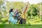 Asian nurse woman sit near senior man on wheelchair enjoy to paint the painting outdoor in the garden and they look happiness