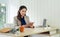 Asian office manager with brown suit holding tablet computer in her hand. Morning work atmosphere in a modern office