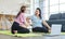 Asian old senior chubby pensioner retirement mother sitting on yoga mat having backache from stretching via online lesson when