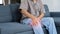 Asian old senior elderly unhealthy sick sitting on sofa at home alone holding hands on knee having emergency painful joint