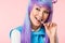 Asian otaku girl in wig eating lollipop isolated on pink