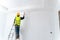 Asian painter man painting the wall in an unfinished building, with paint brush and bucket, isolated on big empty space with