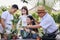 Asian parent, pretty daughter, and grandpa helping planting together for planting trees at home garden. Happy and enjoy the family