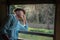 Asian passenger wearing hat looking out of train window