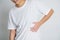 Asian people in a white t shirt on a white background hold hands on his stomach, liver pain, pancreas, kidneys problems