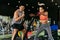 Asian personal trainer coaching a bodybuilding woman to perform crossfit battle ropes exercise in the fitness gym