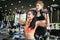 Asian personal trainer coaching a bodybuilding woman to perform the weightlifting exercise with dumbells in the fitness