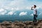 Asian photographer man Standing on a rocky mountain Which looks like a button, he is drinking water from a plastic bottle