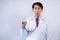 Asian physician holding stethoscope and examining over light blue background.