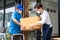 Asian Postman deliver food ingredient box to restaurant waiter in cafe. Attractive barista worker wear mask due to Covid-19, sign