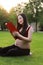 Asian pregnant woman Chinese read red cover book sit on grass lawn in nature outdoor sunshine sunset sunrise day enjoy peaceful