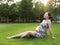 Asian pregnant woman in Chinese traditional cheongsam chi-pao sit on grass lawn in nature sunshine sunset day enjoy free relaxed