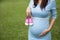 Asian pregnant woman holding a pair of pink toddler shoes