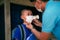 Asian preteen boy looking at his beloved father wearing protective mask puts protective cloth face mask on his face, school child