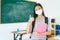 Asian primary student girl thumb up and  wearing masks to prevent the outbreak of Covid 19 in classroom while back to school