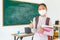 Asian primary student girl thumb up and  wearing masks to prevent the outbreak of Covid 19 in classroom while back to school