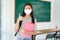 Asian primary students girl thumb up and  wearing masks to prevent the outbreak of Covid 19 in classroom while back to school