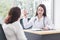 Asian professional doctor woman who wears medical coat talks with woman patient to suggest treatment guideline and healthcare